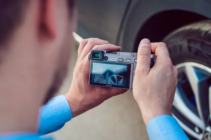 Michael Dorzweiler fotografiert mit einer Systemkamera das Rad eines Autos, Blick über die Schulter